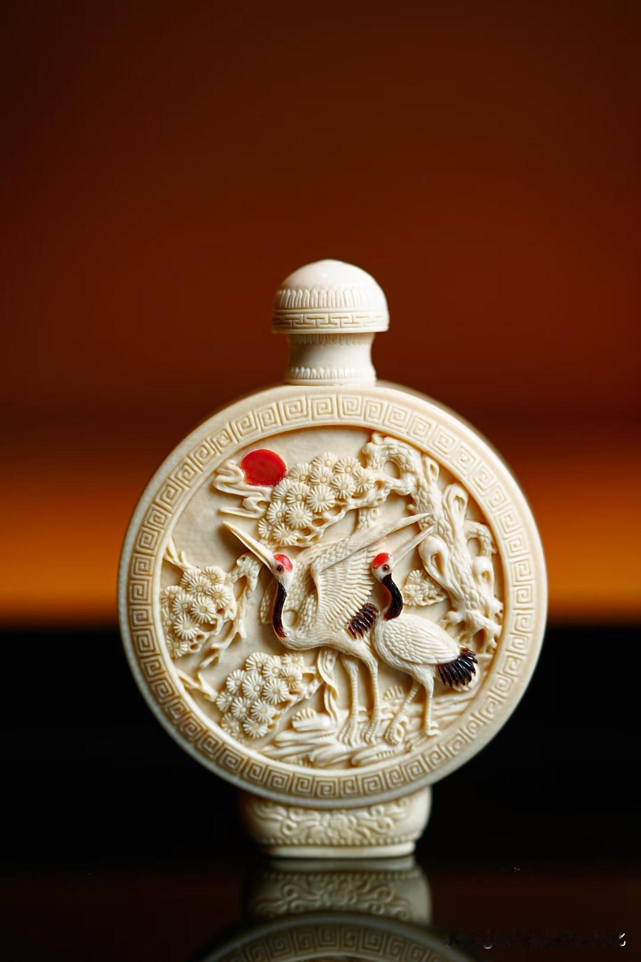 这一枚鼻烟壶，小，却不简单。

猛犸牙温润如玉，松枝舒展，仙鹤相对，
一轮红日点