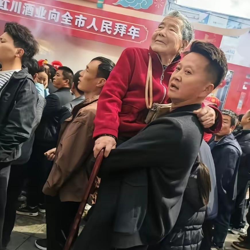 演出现场，别人家大多是大人抱着孩子，可有一幕却格外吸睛：一个小伙子稳稳抱着妈妈在