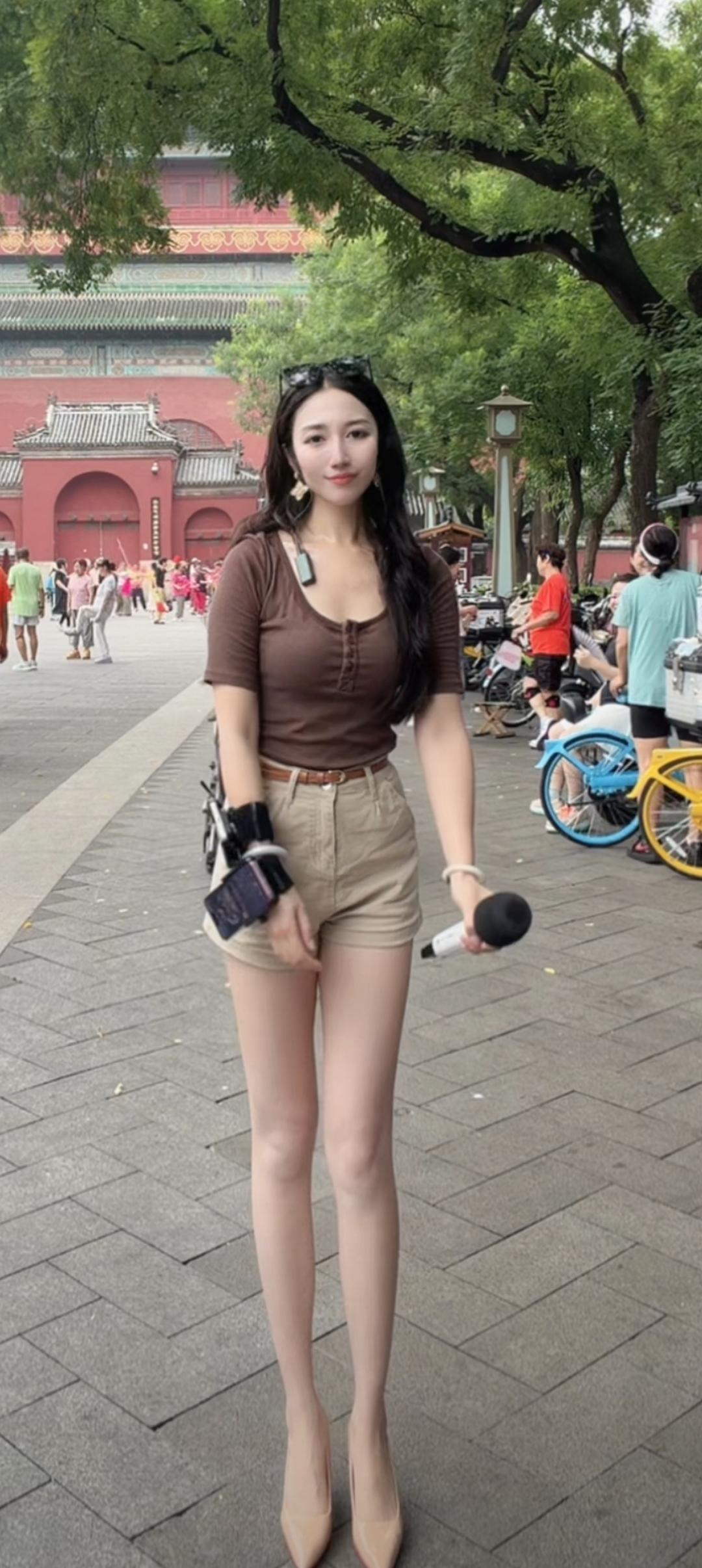 这姑娘拿着话筒站在户外。