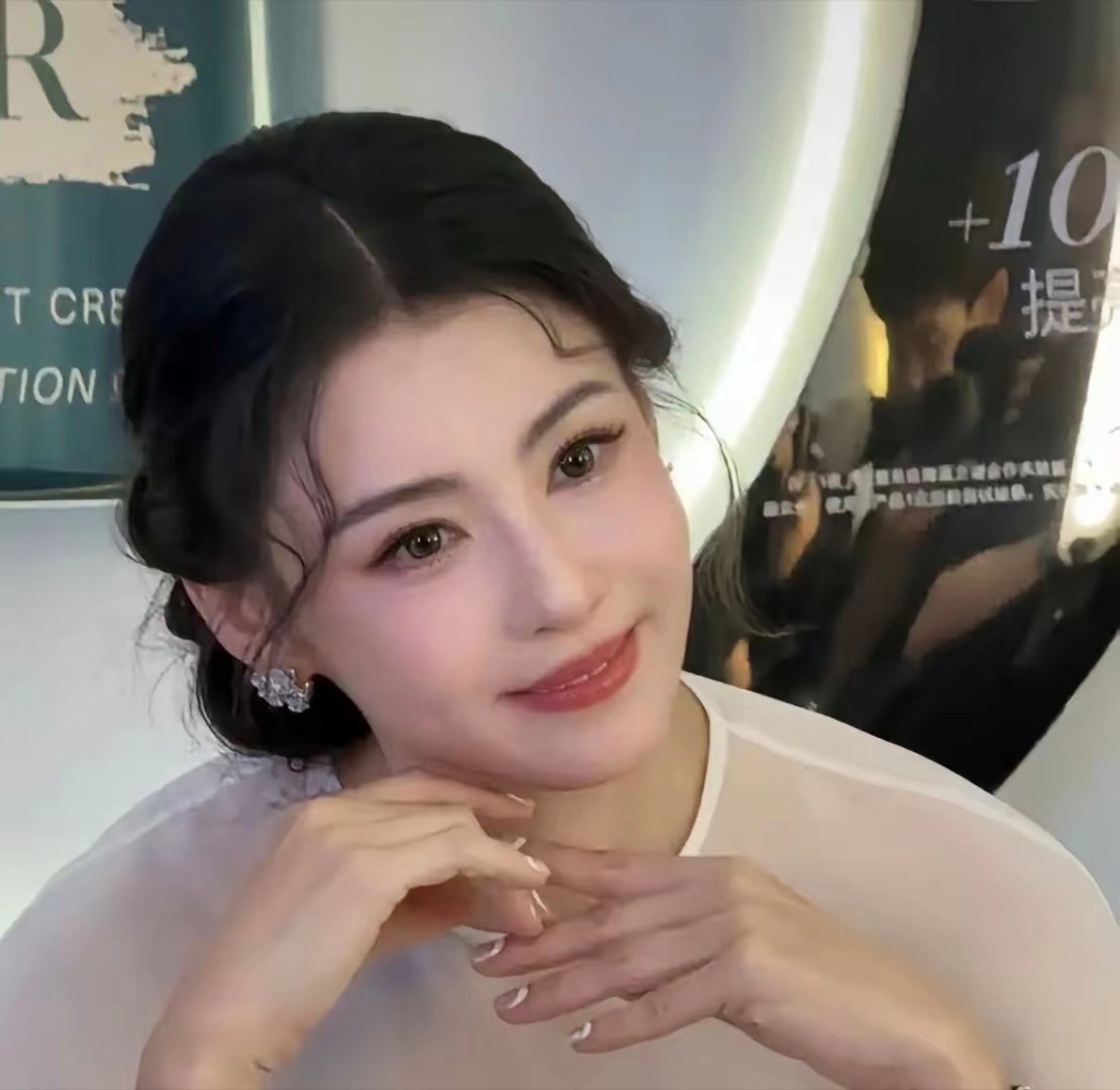 她一头温柔盘发，几缕碎发轻轻落在脸颊两侧，脸部饱满圆润，再加上宽松长裙，看上去胖