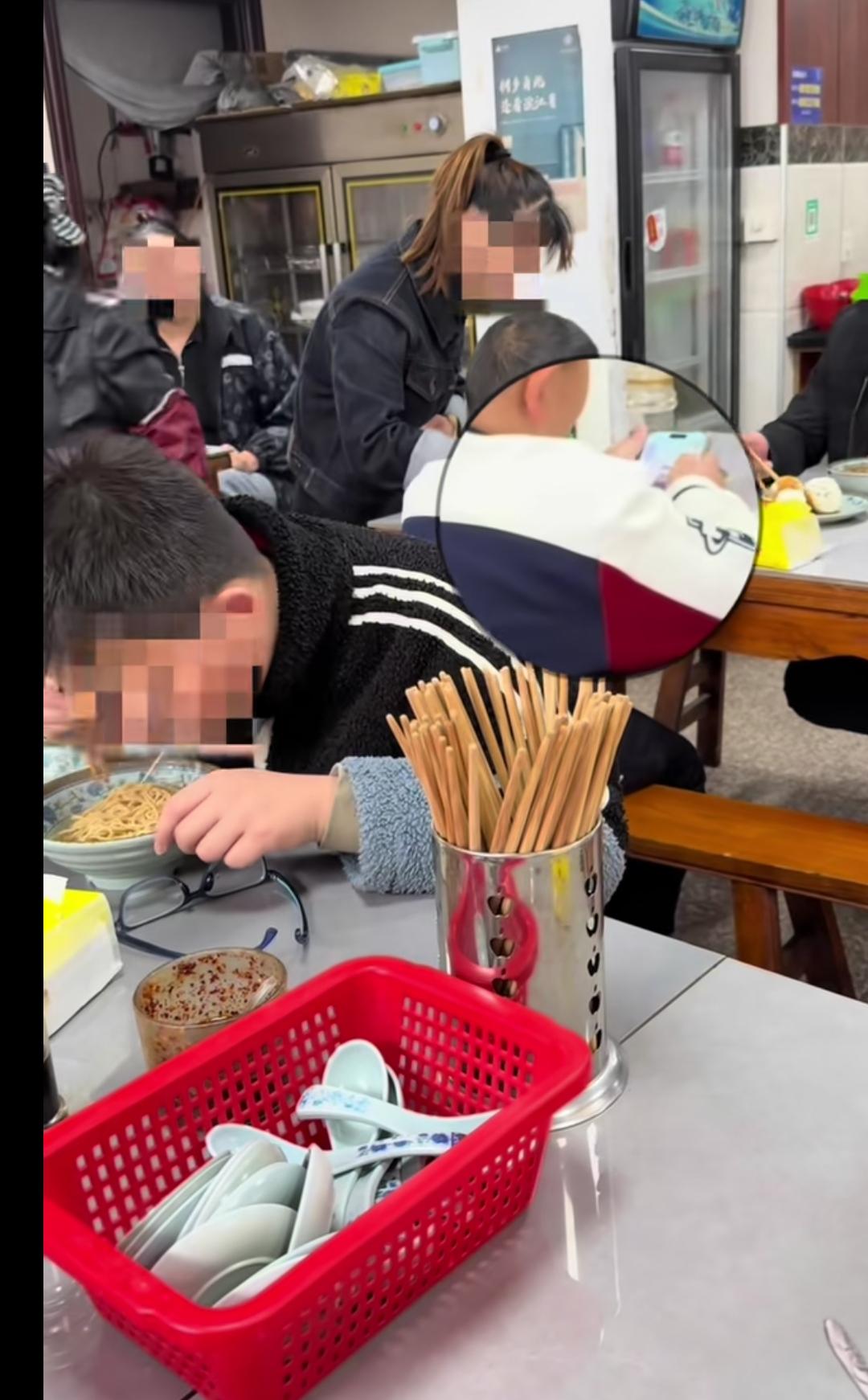 惯子如……
这个孩子这么大了，一边玩着手机，左边的应该是妈妈，在喂着饭。看起来应