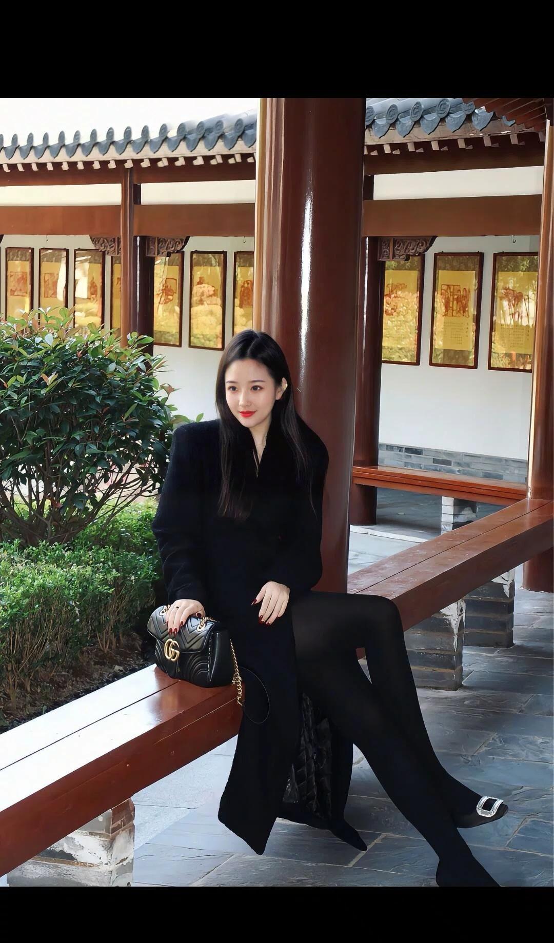 黑衣美人坐长椅，古风庭院显优雅