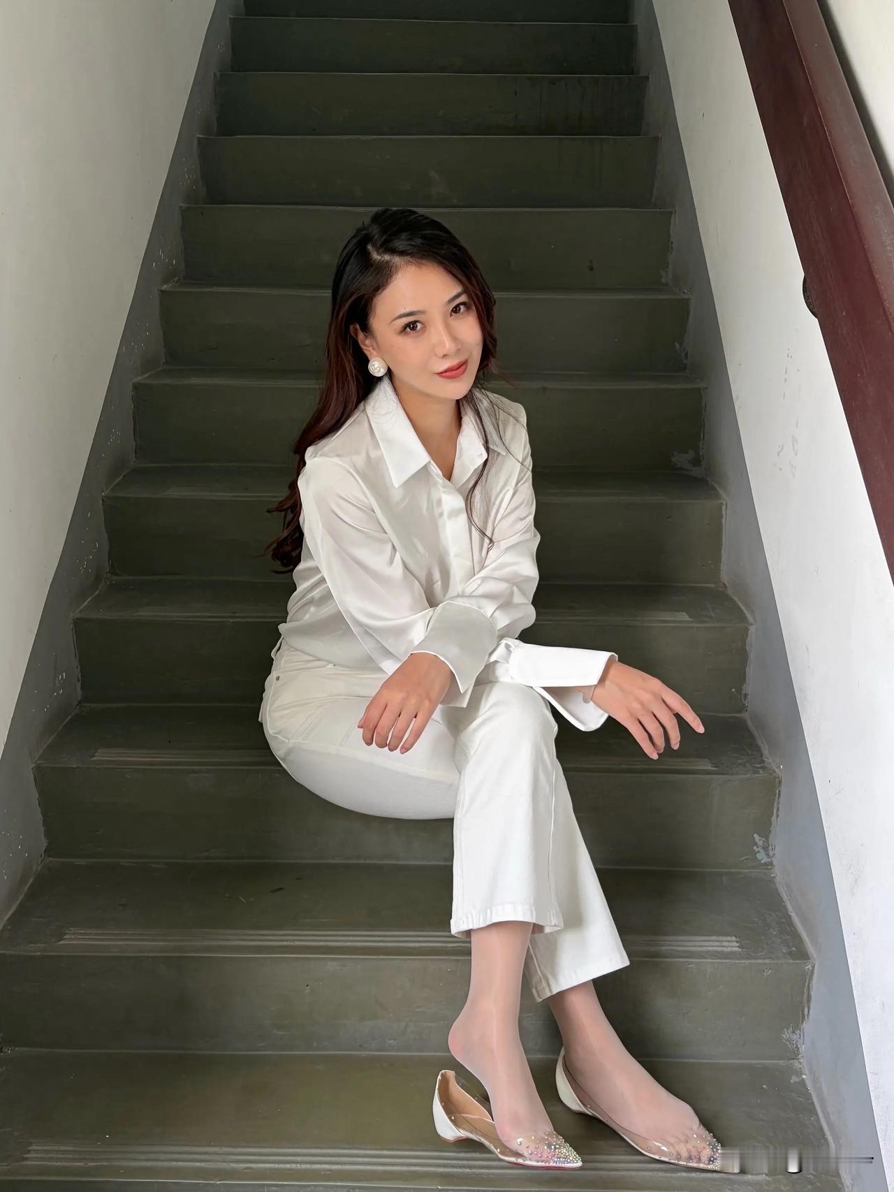 一位穿着白色套装的女士坐在楼梯上。