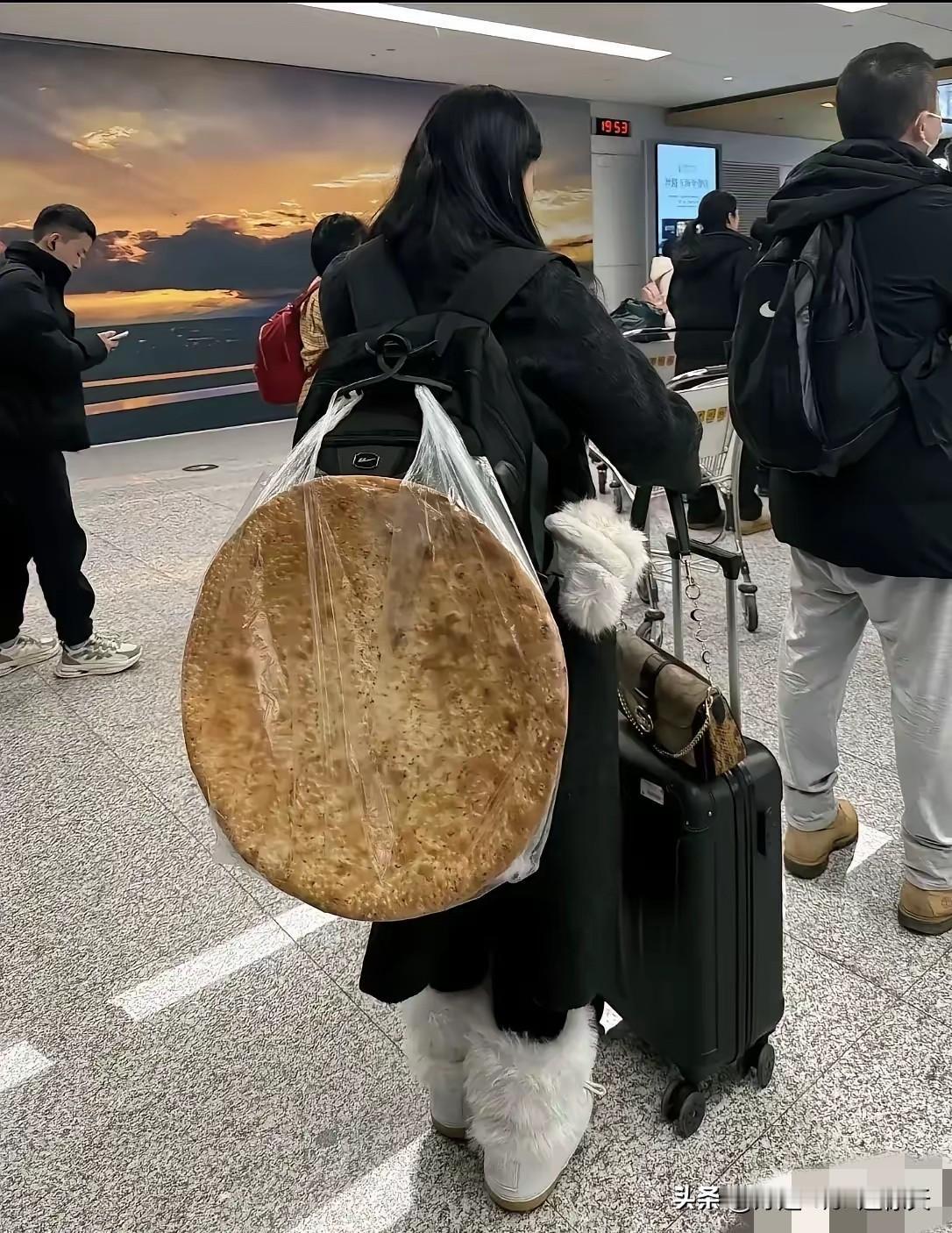 一女子在机场等着过安检，万万没想到女子的背上竟然背了一个硕大无比的馕，远看这馕占
