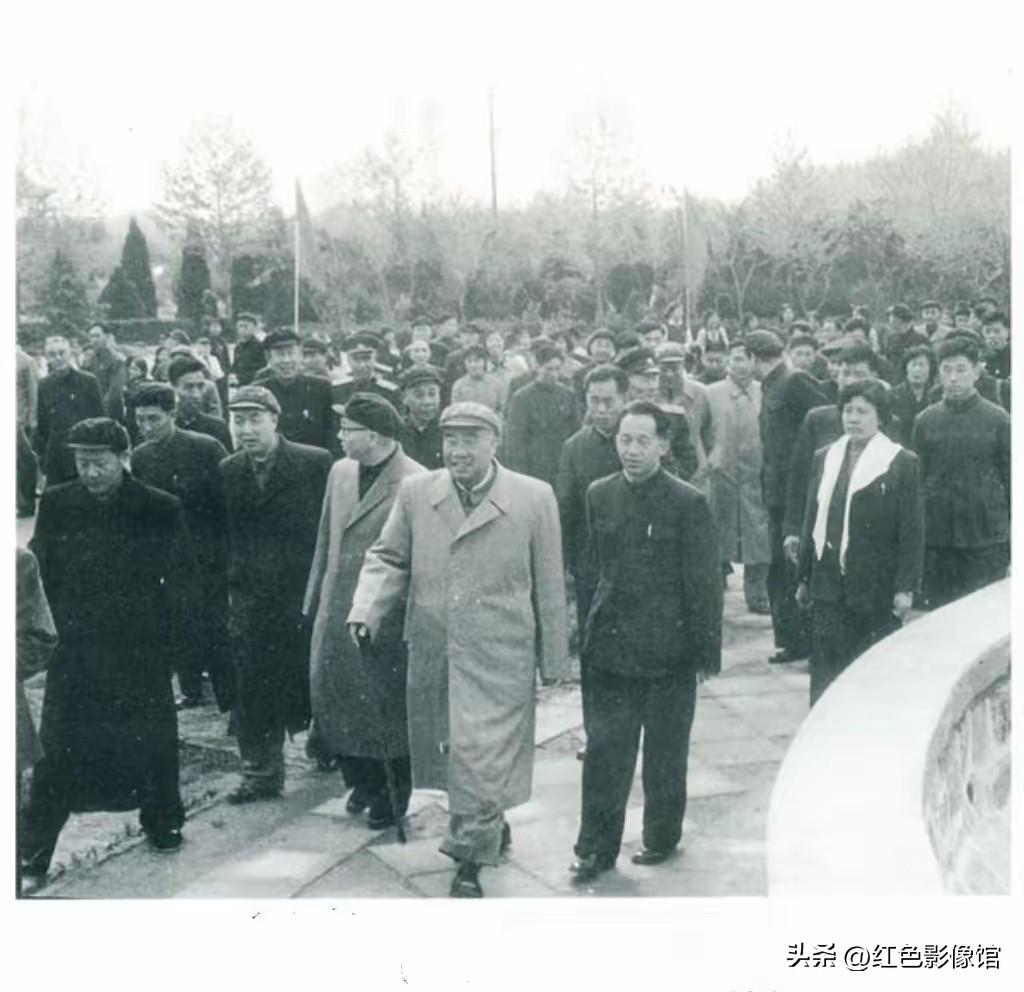 这张黑白老照片拍摄于上世纪五六十年代，朱德元帅身着长大衣、持手杖行走于户外，身旁