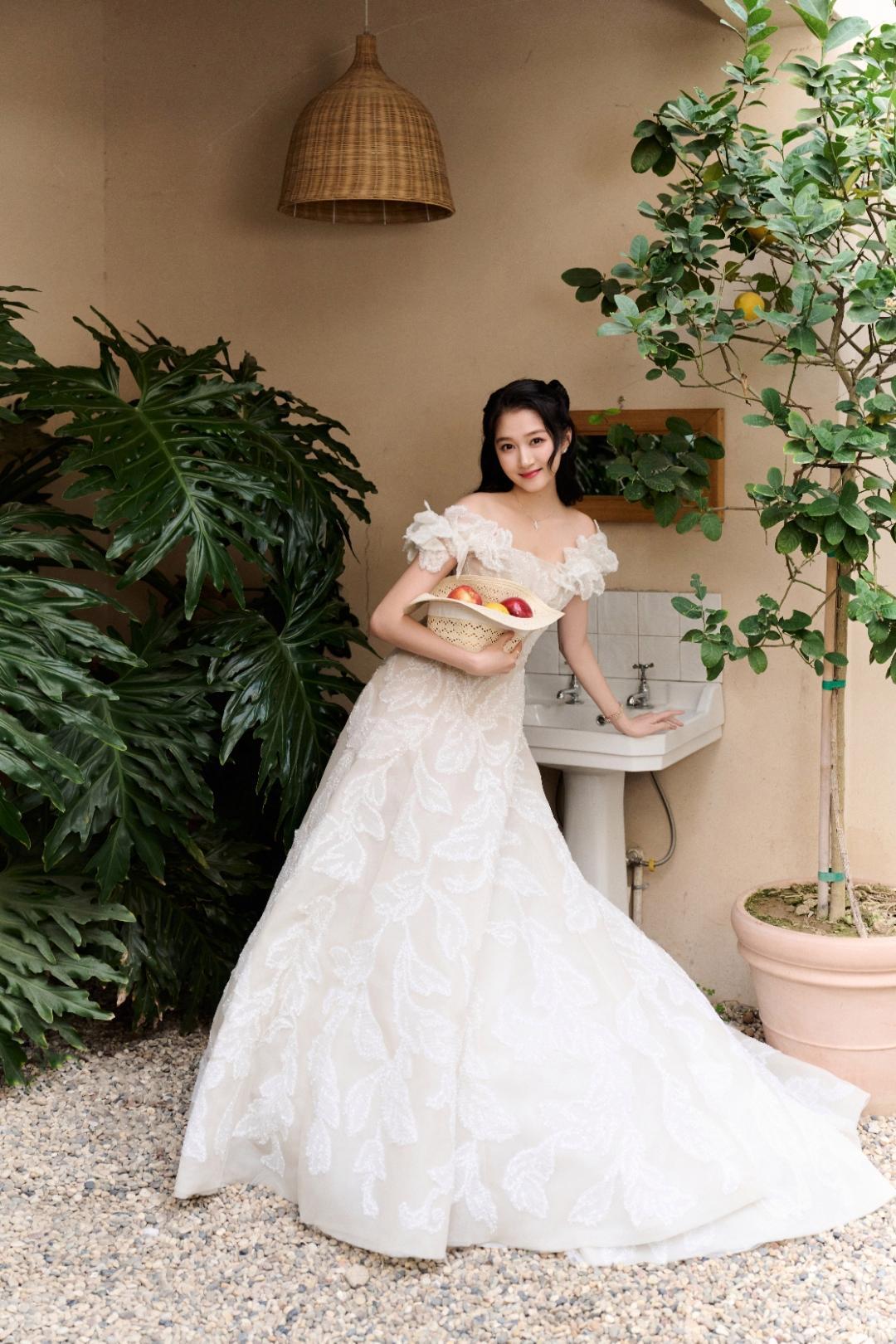 在暖调的法式庭院里，关晓彤身着一袭重工白纱惊艳亮相。柔美的一字肩设计缀满蕾丝褶皱