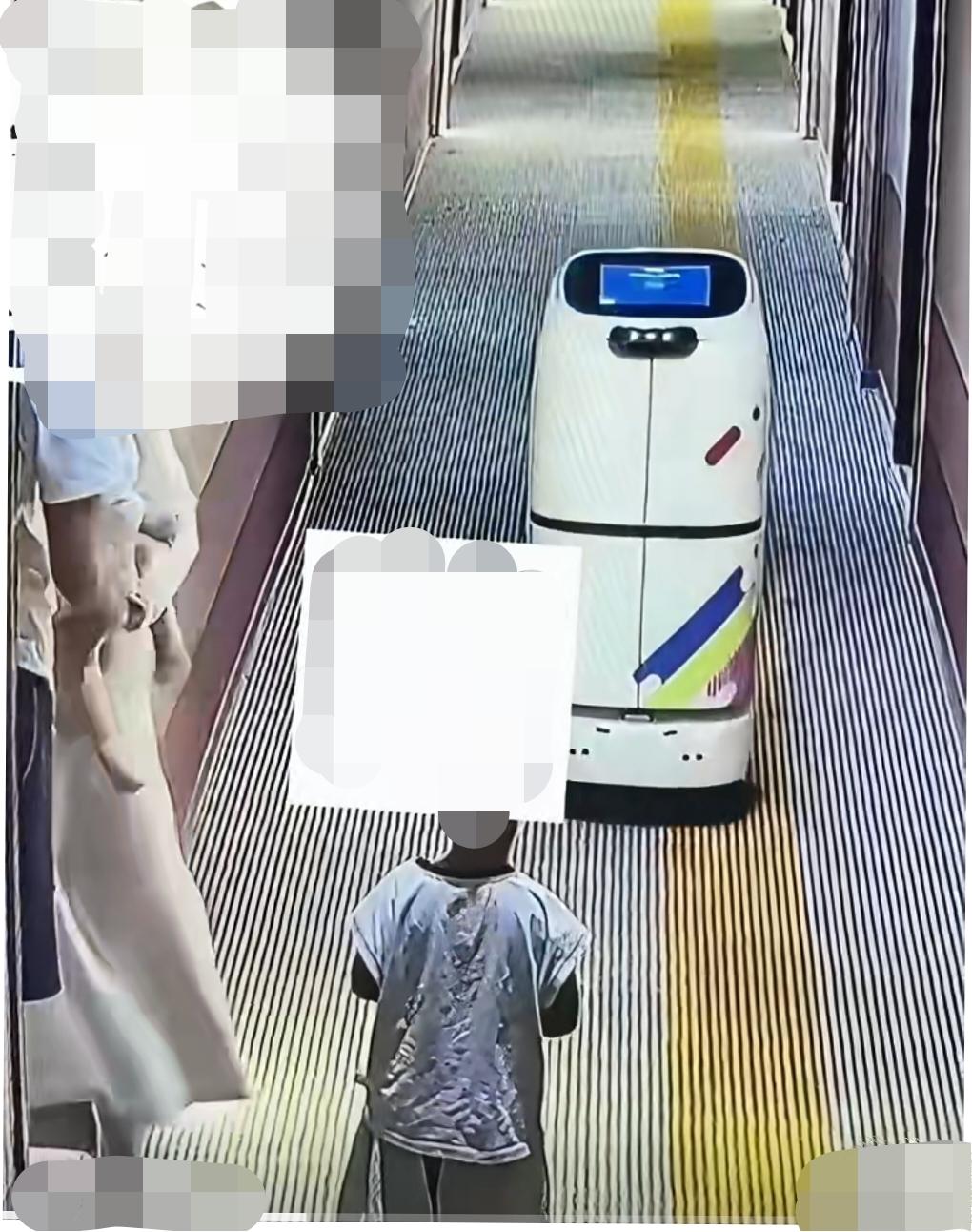 某酒店内，智能配送机器人正在楼层内工作，一名小男孩站在走廊正中间好奇观看，配送机