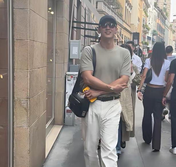 黄景瑜一件肥大的白色长裤搭配紧身圆领T恤衫，背着背包，现身米兰街头。他笑容灿烂更