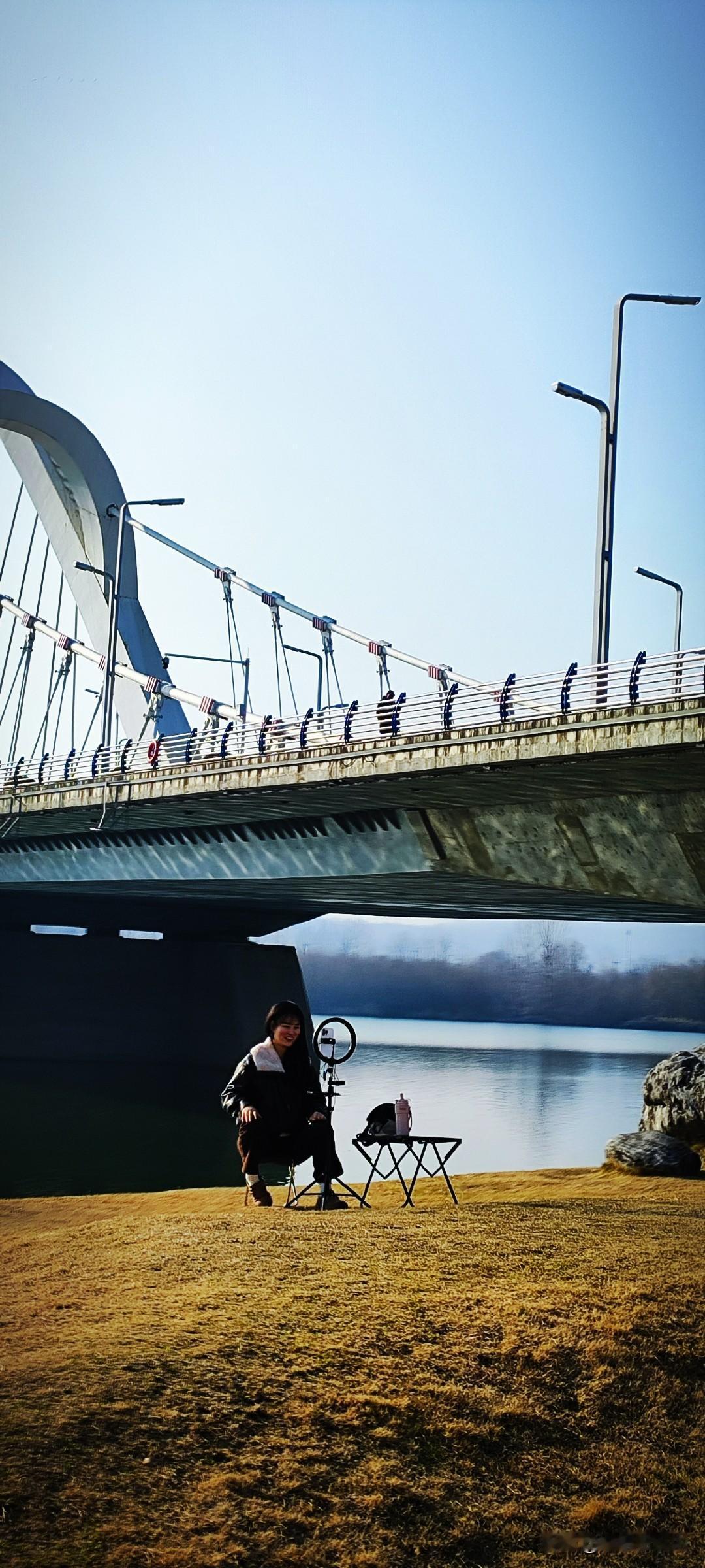晒图笔记大赛草坪上，小姐姐在直播。龙岗大桥横跨水天一色的汉江，这般美景打底，难怪