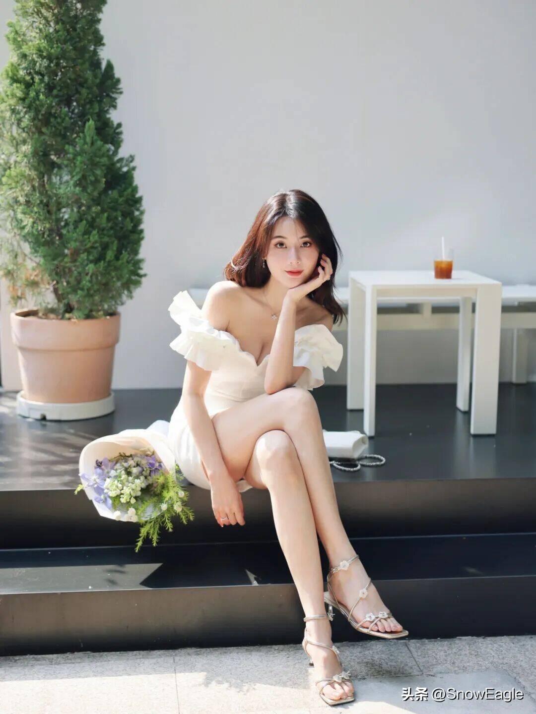 一个穿白色裙子的女生在阳光里拍照。