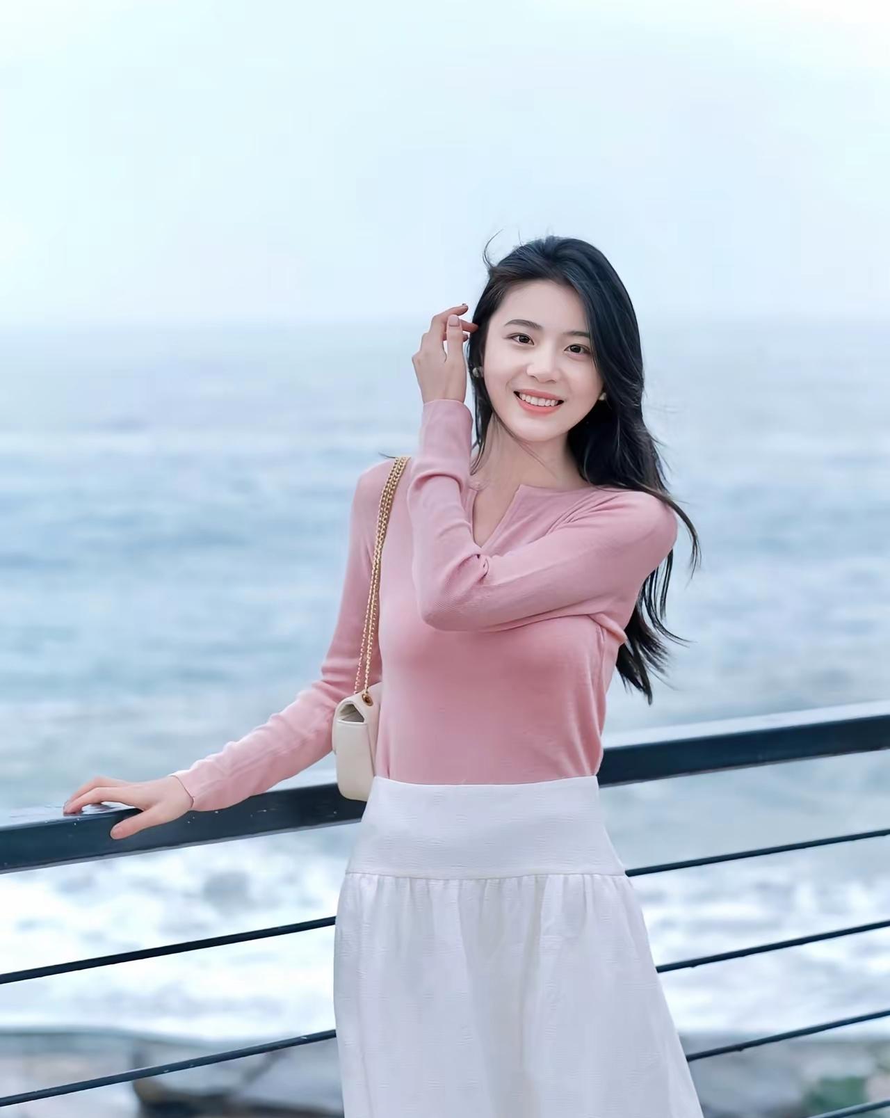粉色毛衣搭配白色长裙，温柔优雅，享受海风拂面的美好时光。