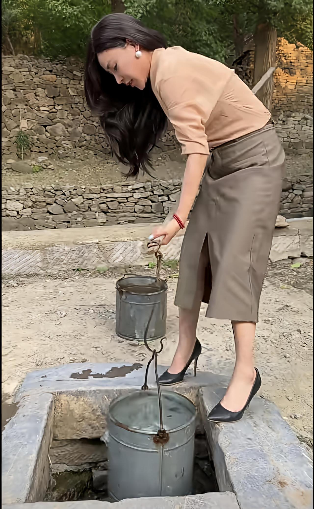 分享令人心动的美照如图所示，这位女士能用这样的方式，将满满一桶水从水井里吊上来，