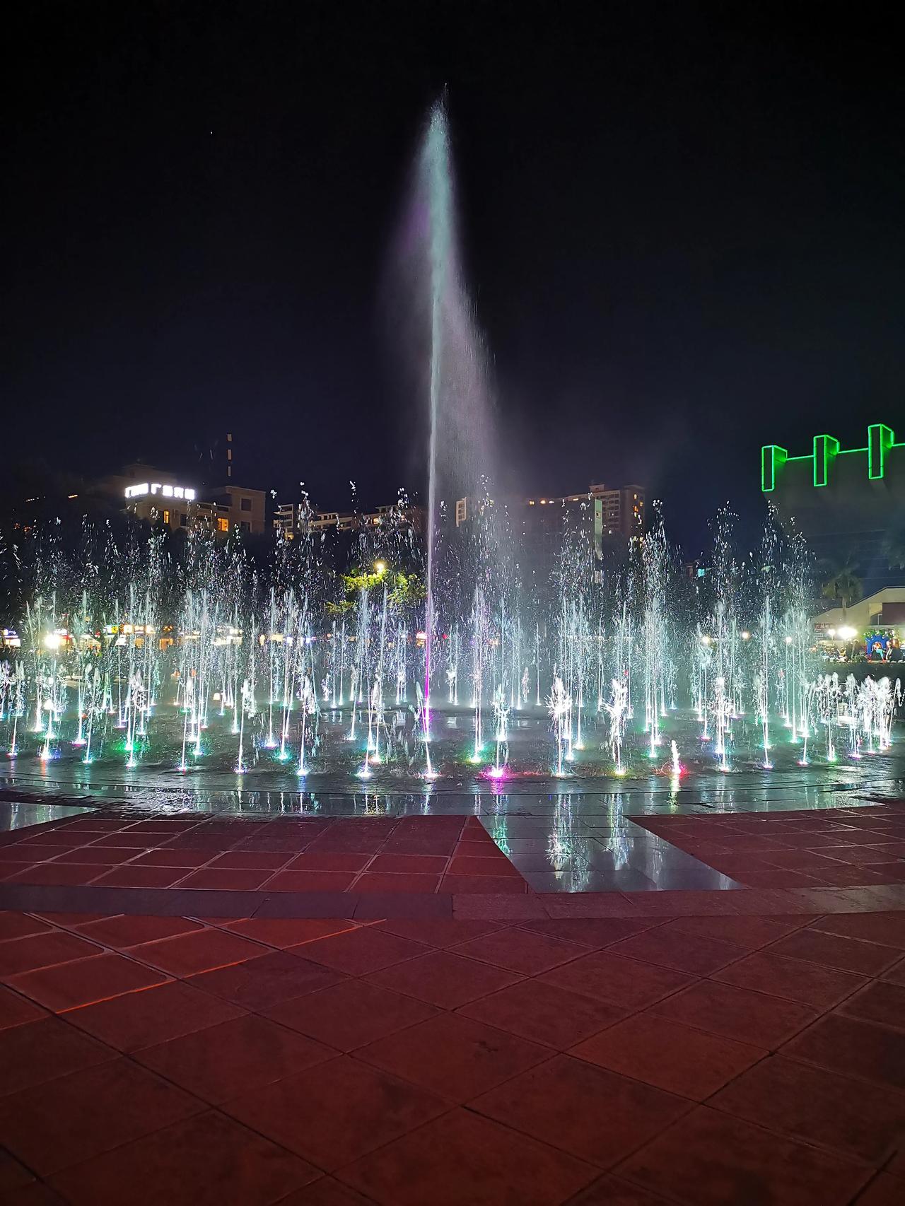 旅居元江掠影（3）
  夜色下的太阳城广场。只见广场中央彩色喷泉的水注，时而高，