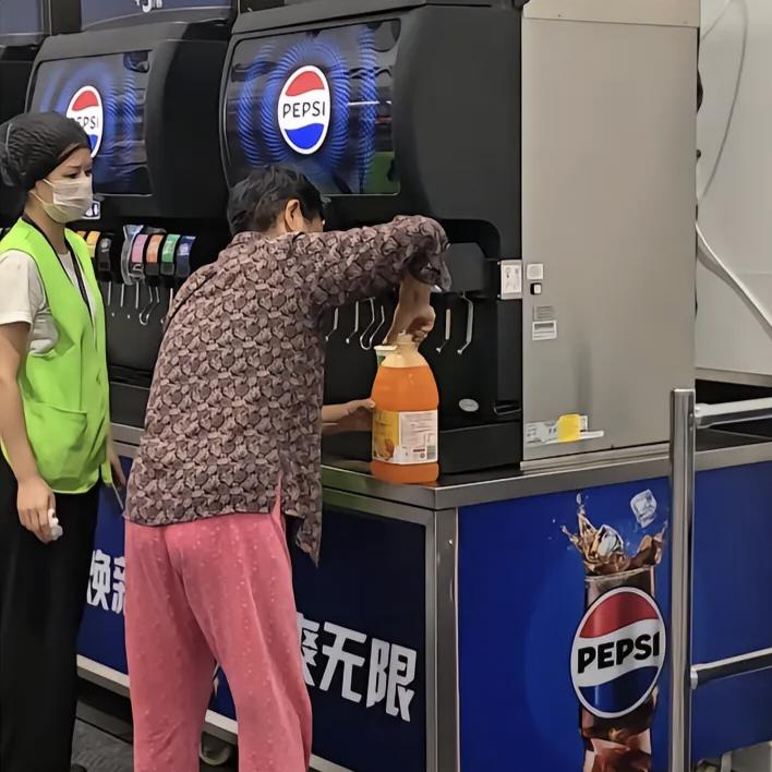 山姆超市推出饮料免费续杯活动，大爷大妈们纷纷提着桶来接饮料，准备带回家。山姆员工