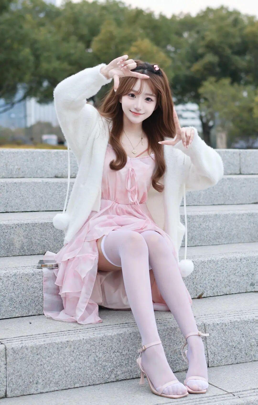 背景是模糊的绿树与远处建筑，营造出清新自然的氛围，阳光柔和地洒在她身上，使整个画