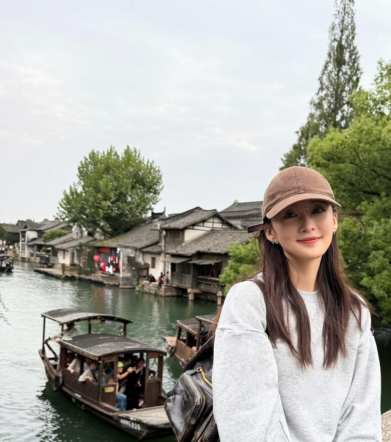 李沁漫游乌镇，
浅灰色运动套装配咖色棒球帽，
戴金属框眼镜，
温柔可人，
又美又