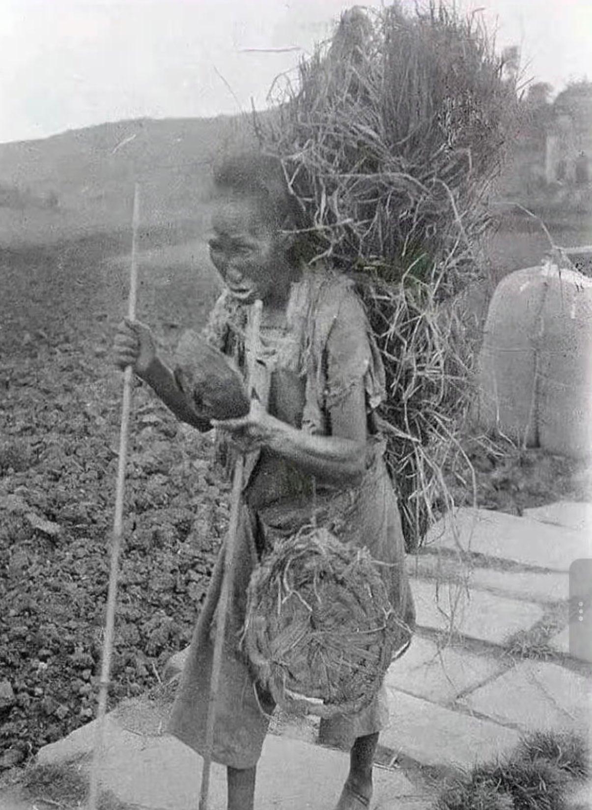 一张摄于20世纪40年代旧中国四川金堂县的黑白照片，画面中一名衣衫褴褛、背着一大