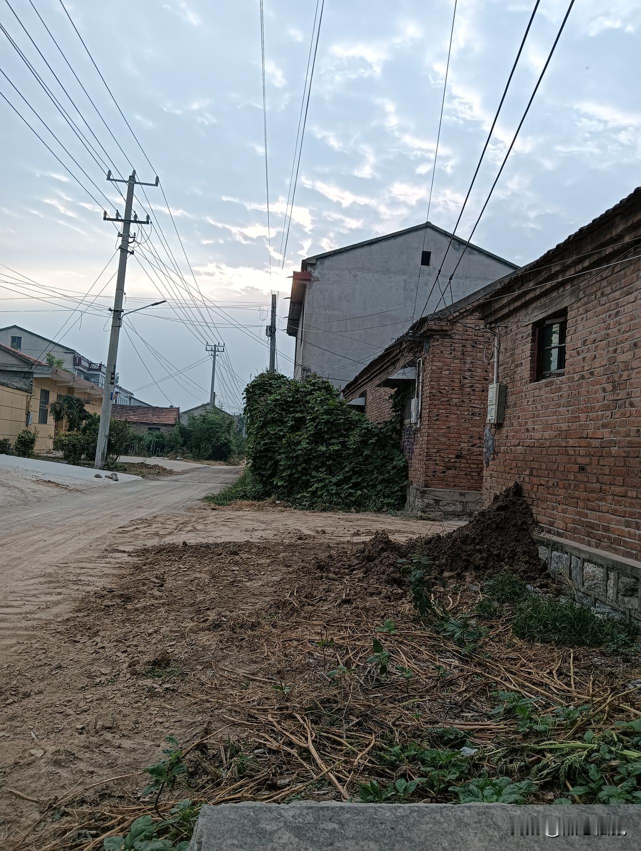 乡间小路，两边是砖房和电线杆。