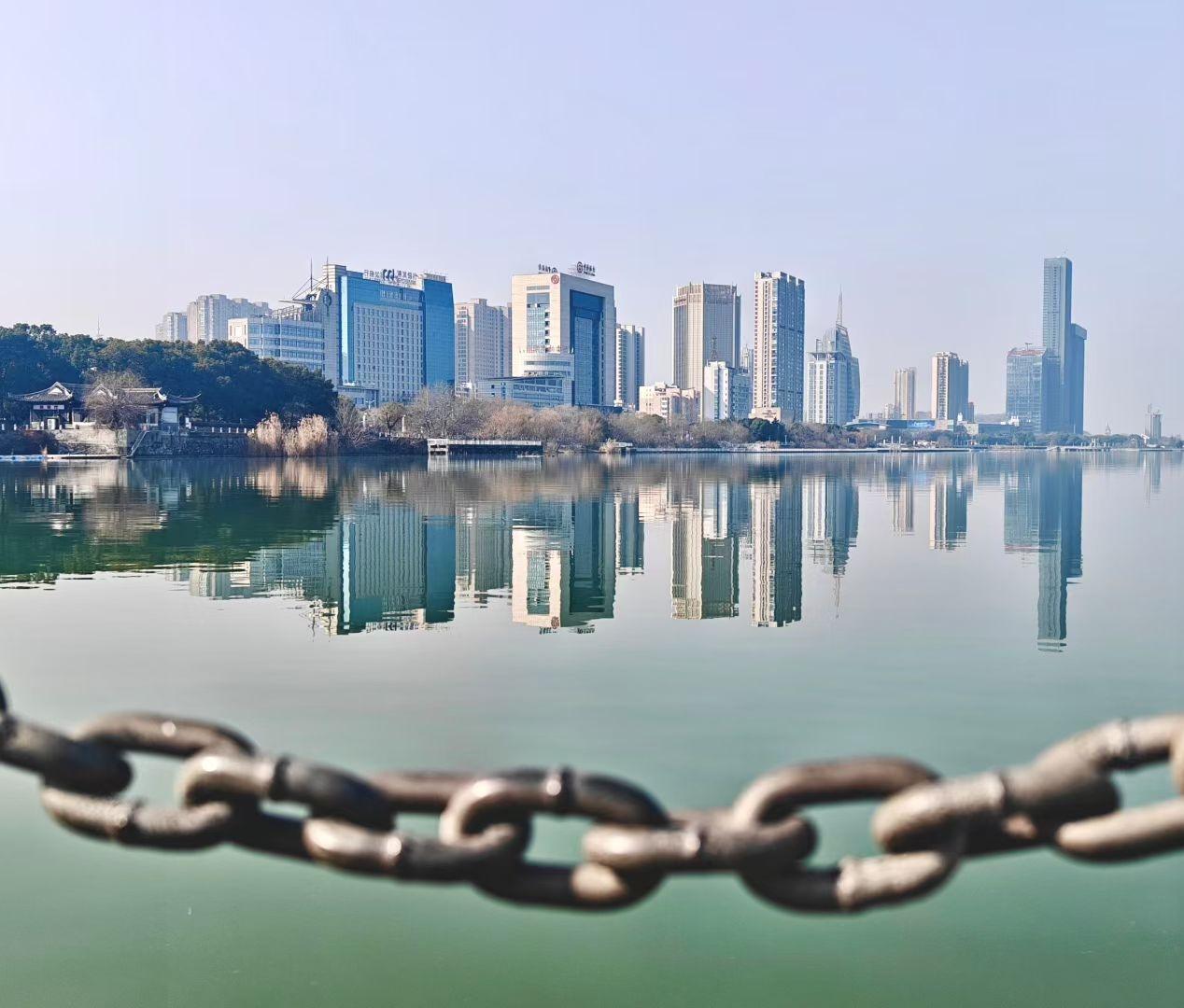 江水如镜，将城市的轮廓温柔铺陈。身前的铁链锁住旧时光，身后的高楼续写新故事，一静