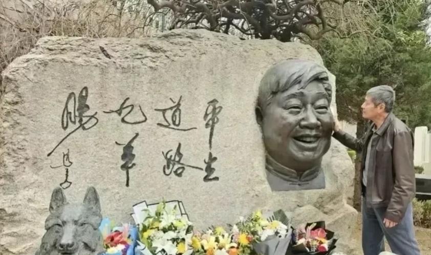 马季墓前，徒弟刘伟摸着师父的铜像脸，半天舍不得走。碑上刻着 "平生道路九羊肠"，