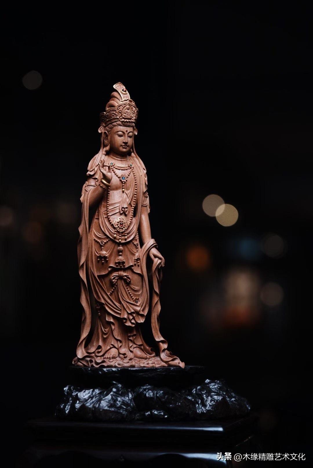 老山檀香的沉稳木色，衬出观音立像清雅脱俗的气韵。面容宁静，身姿修长，一手结说法印