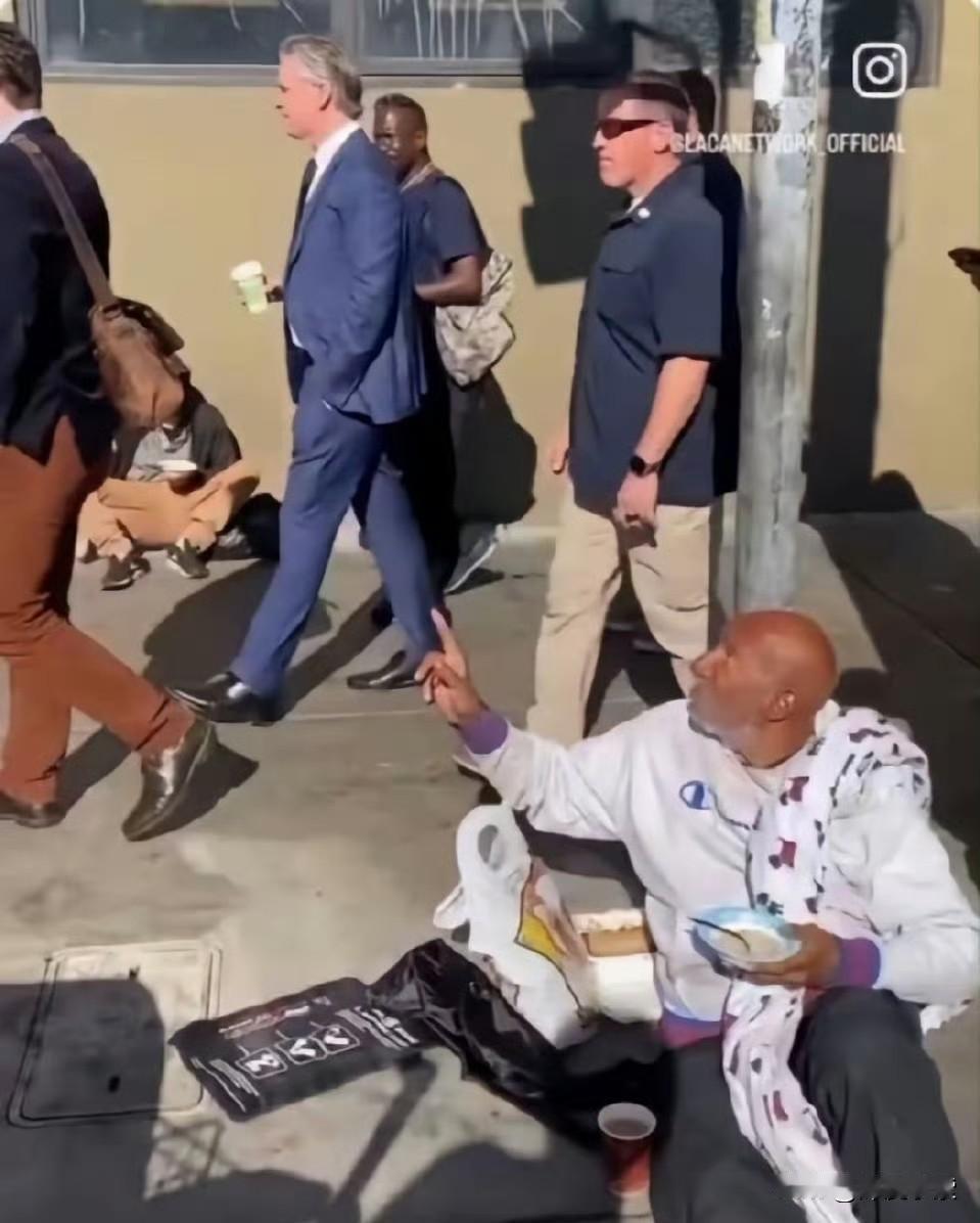 加州州长纽森单手插兜，在保镖簇拥下从美国流浪汉身边淡然走过，手里还拿着一杯咖啡[