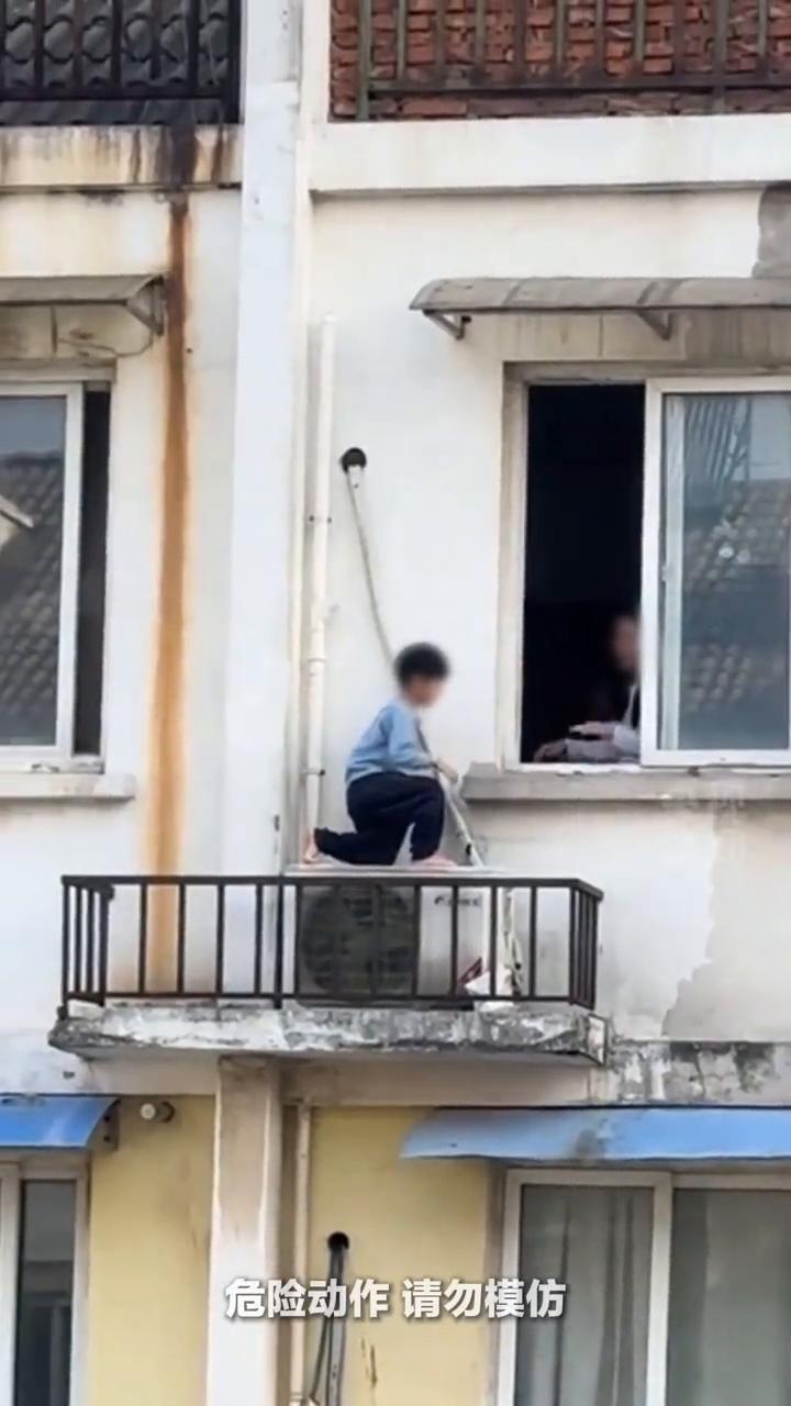 男孩翻到窗户外玩耍，妈妈强压怒火引导孩子回屋。
不要上去。窗边无小事，看护不能松