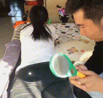 真是天气变热了。女人趴在床上看手机，她的丈夫拿了个放大镜，然后将聚光点对准在了女