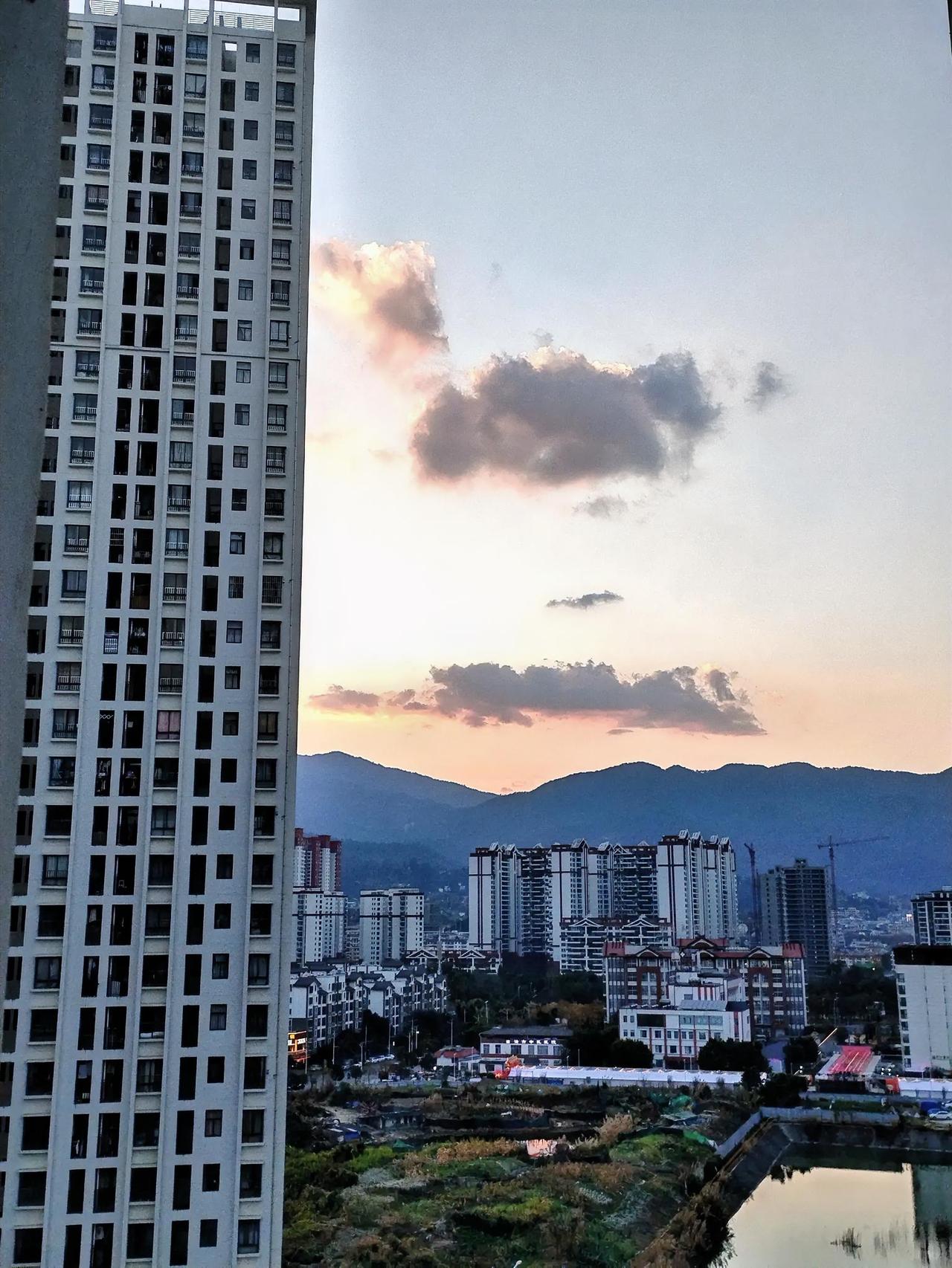 城市的黄昏，高楼鳞次栉比，云霞映照其间，宁静又迷人。夕阳缓缓西沉，我于家中望向窗