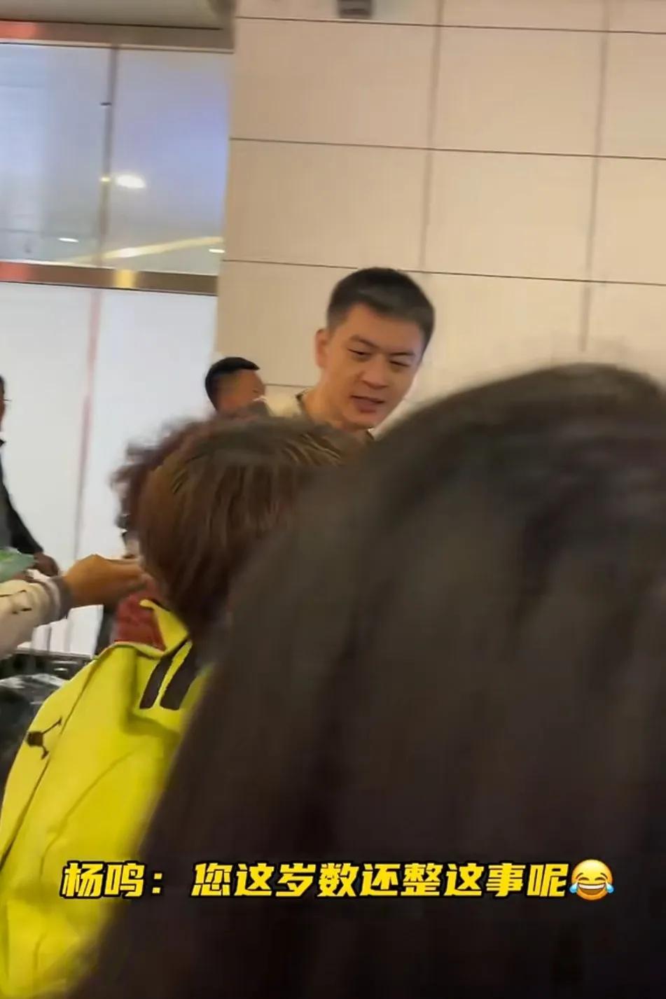 杨铭从机场出来，有个大妈粉丝找他合影，他看看大妈说，你都这岁数还整这事呢啊。表情