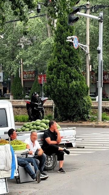 河南街头，三个卖瓜大叔正蹲在马路牙子上聊天，嘴里的烟刚点着。
突然，其中一个黑衣