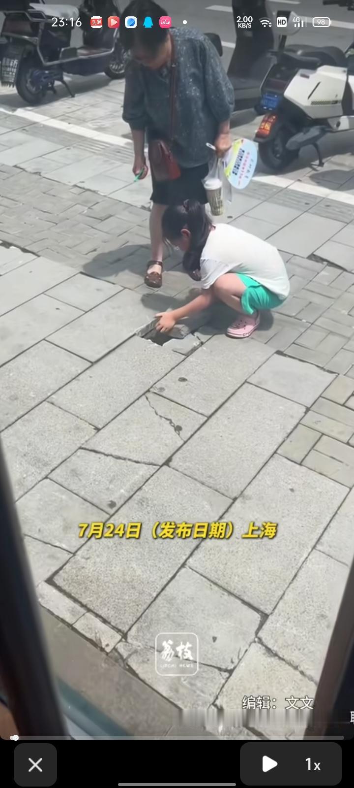 7月21日，上海。网友发视频称，街头上有位小女孩弯腰修整凹起的砖头，奶奶在旁边静