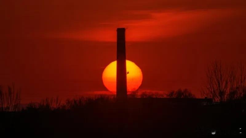 烟囱矗立夕阳中，红霞映照天地间。（安妮拍摄）