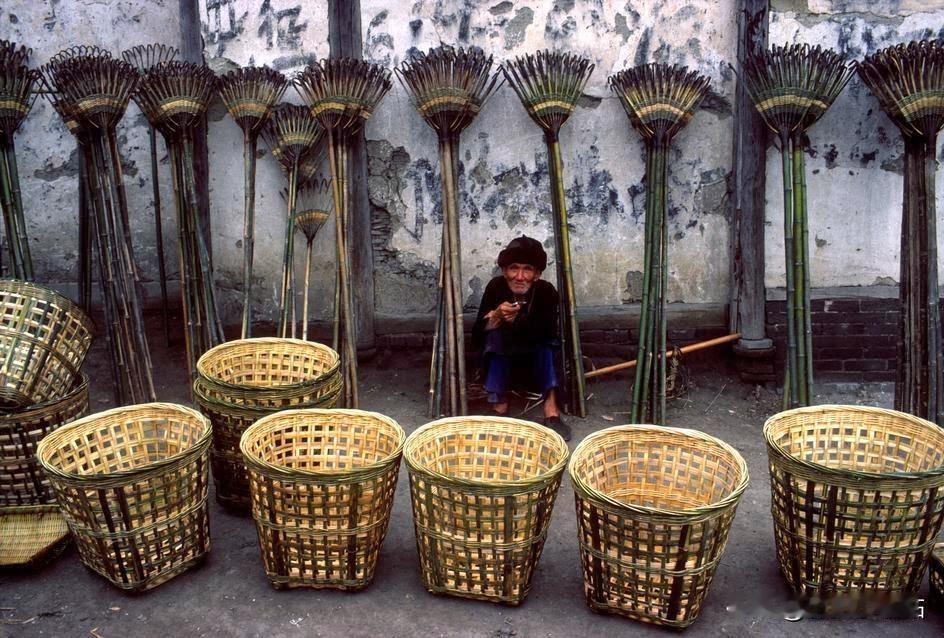 70年代末，一位篾匠老人静静地坐在集市的一角，身旁摆放着他亲手编织的背篓与竹耙子