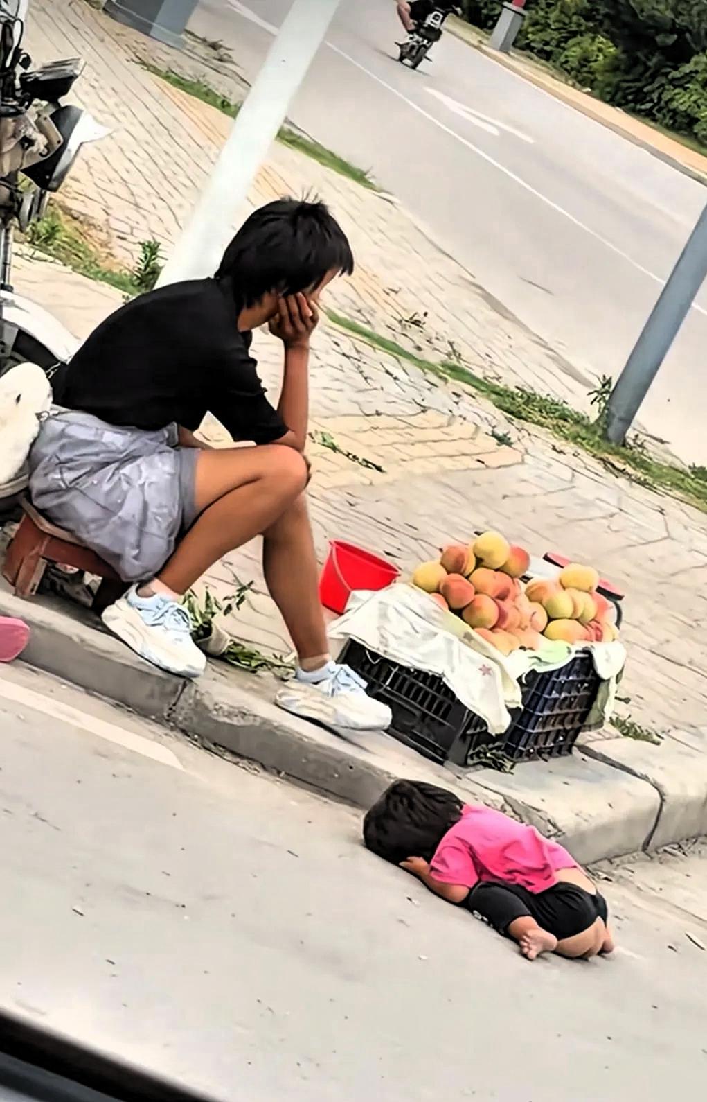 这是谁的女儿，谁的妻子，又是谁的孩子？烈日炎炎下，一名女子坐在街头，面前摆着一筐