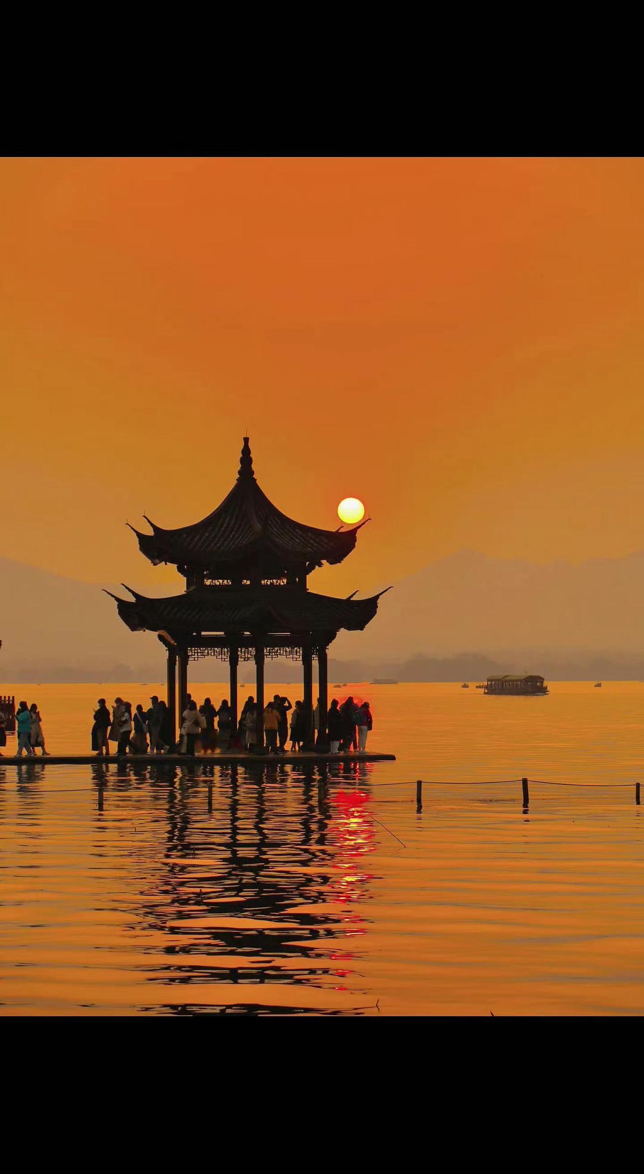 🌇残阳如熔金坠湖心，古亭剪影浸在蜜糖色里🍯。人潮静立成画，喧嚣被揉碎在波光里