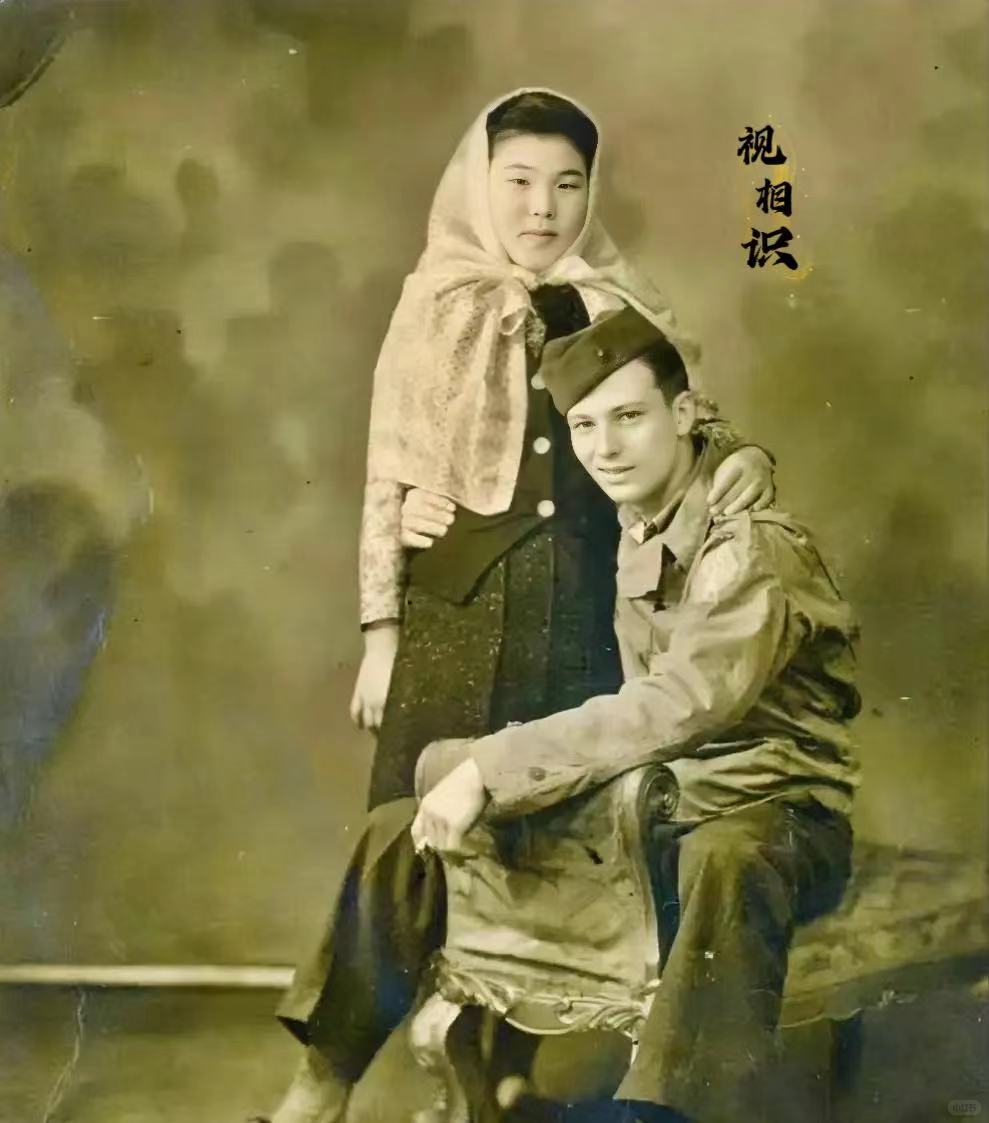 1946年，日本，一美国大兵搂着日本女子的照片，镜头中的大兵穿着军装坐在凳子上，...