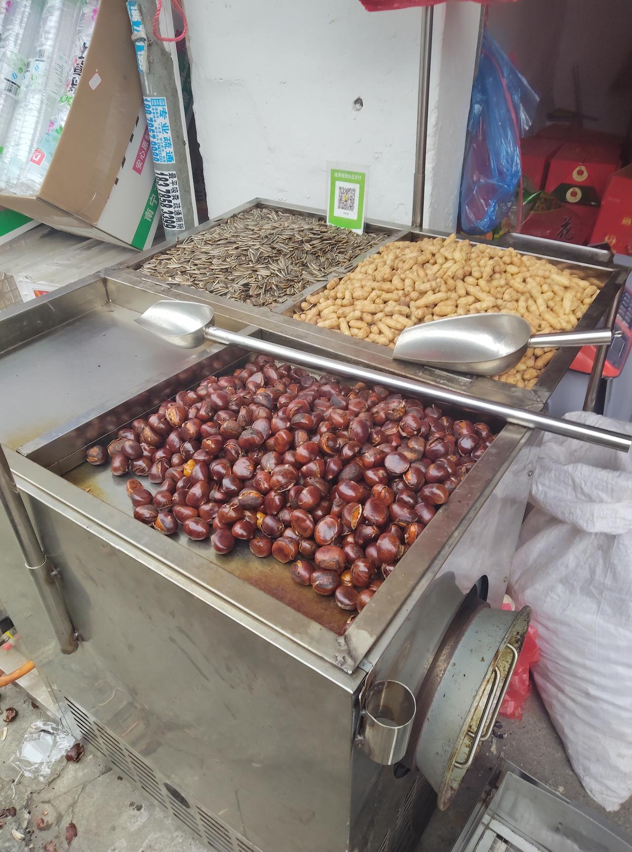 每次路过这种炒货摊，都忍不住停下脚步。刚出锅的糖炒栗子油亮油亮的，热气裹着甜香直