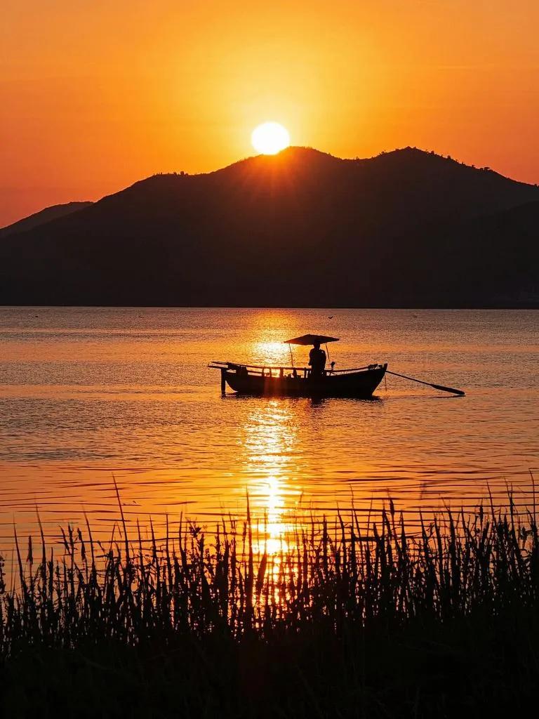 夕阳落太湖，水天金韵浮。扁舟破镜湖光碎，岸畔烟村晚照幽。山川皆醉此中柔。最灿莫过