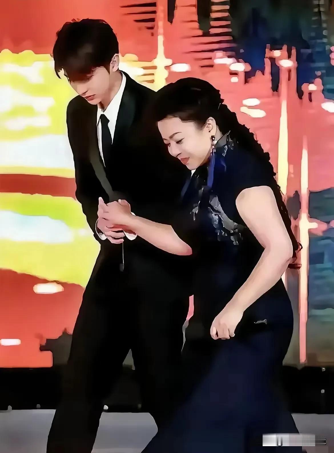 印象当中，照片上这个女歌手也才56岁，怎么还要小伙子搀扶着走路呢！
这到底是主办