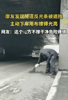 太暖了！一位摩友，在隧道里停下来，拿着块布仔仔细细擦着反光条。那些条子被灰尘盖得