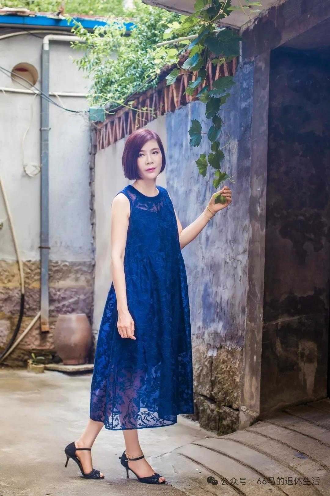 穿蓝色裙子的女士在巷子里拍照。