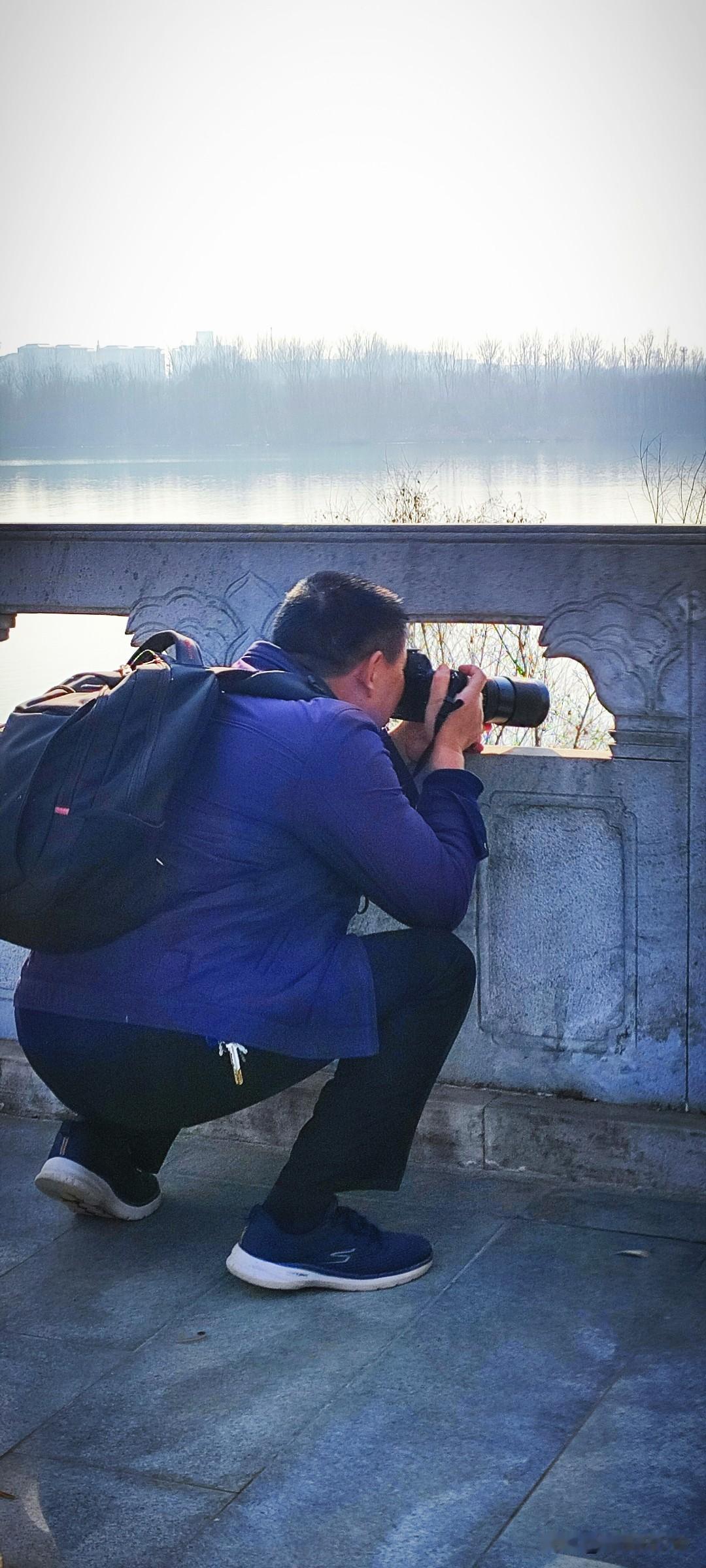 今年冬天的不同一位摄影爱好者在这里蹲拍江面上飞过的水鸟，透过树梢，映着波光粼粼的