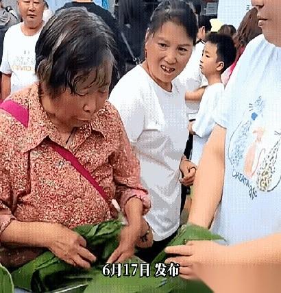 社区组织大伙包粽子，满满一不锈钢盆泡好的青色粽叶刚端上长桌，旁边一位大妈胳膊一伸