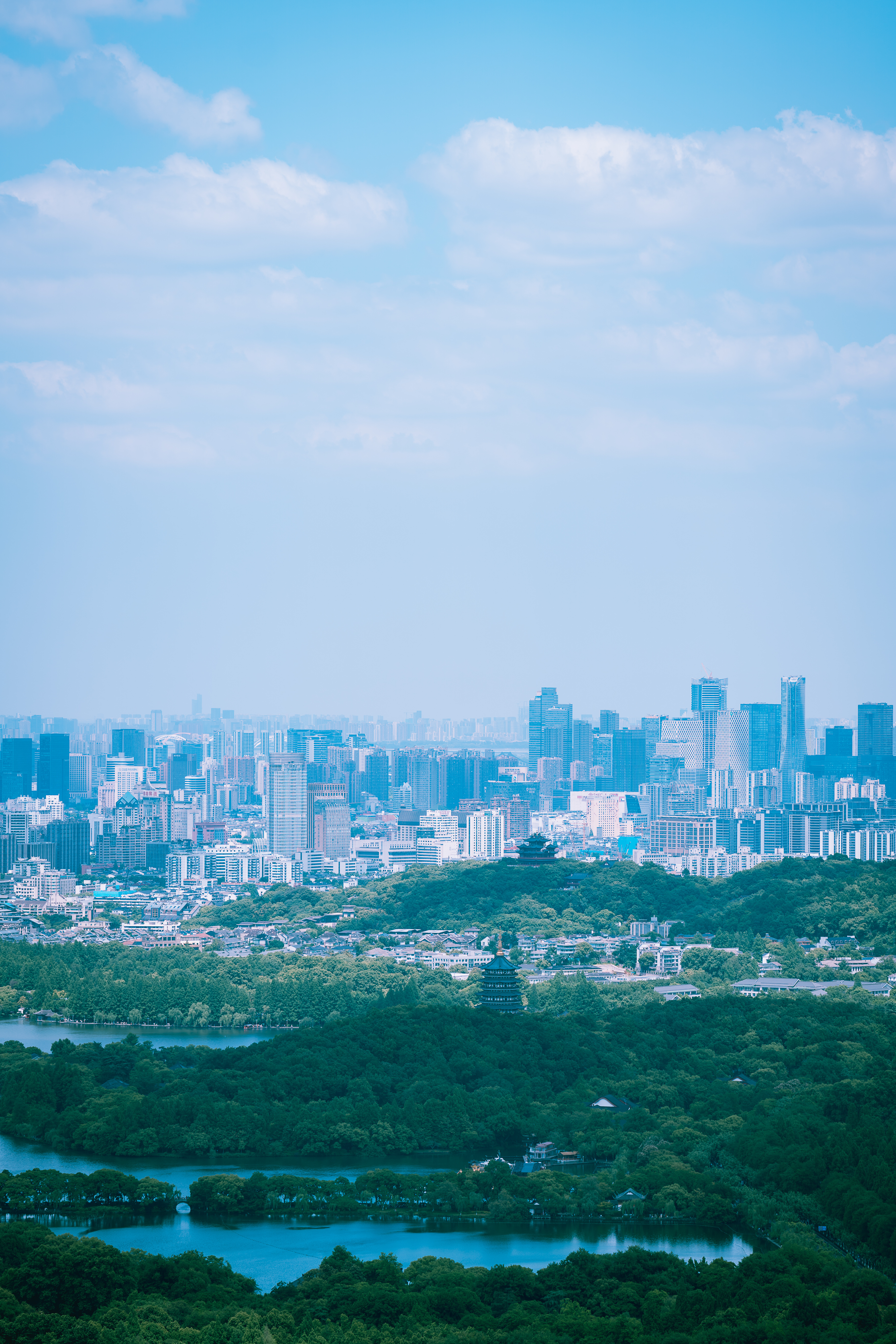 站在南高峰上，镜头朝东北方向俯瞰西湖，前景是苏堤、雷峰塔，中景吴山城隍阁，远景杭