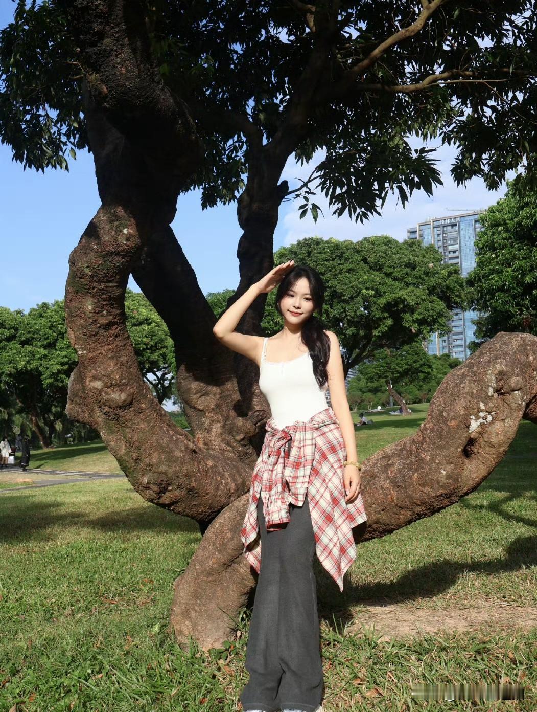 阳光明媚，她站在大树下微笑。