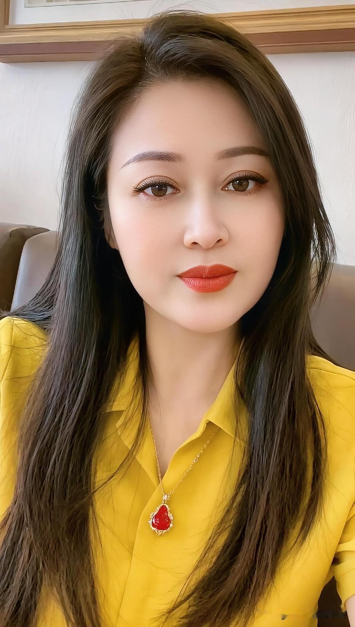 明黄衣袂绽春日暖阳，墨发垂落似夜瀑流芳。红唇点染温柔，朱坠凝光，眉眼间藏着岁月酿