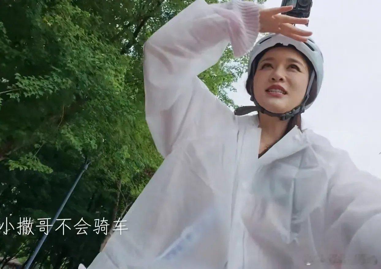 下雨天众人骑自行车，其他人都双手紧握车把冒雨前行，陈乔恩却单手掌控龙头，另一只手