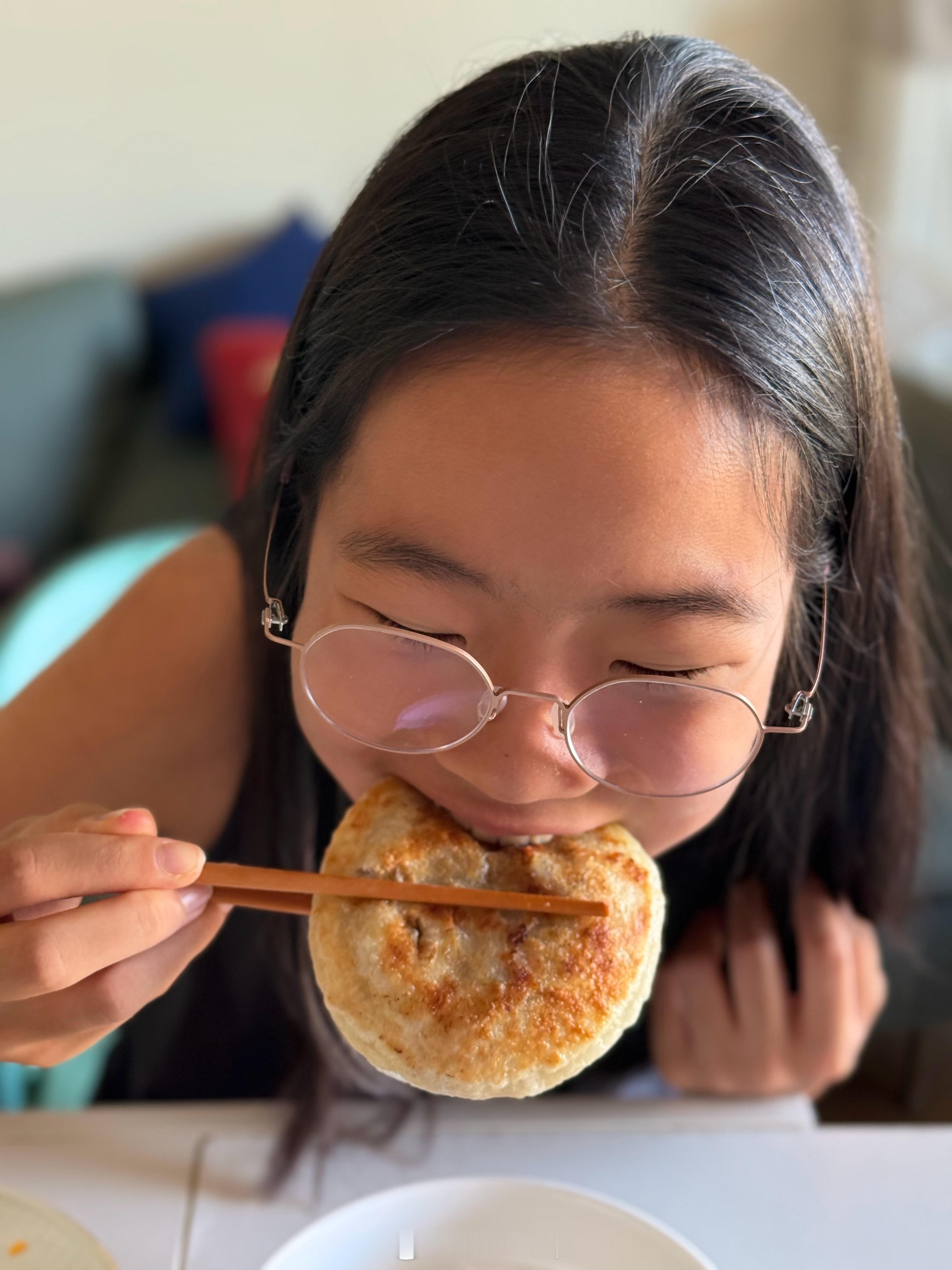 拥有非常健康自然肤色的小学生在吃她最爱的早餐牛肉饼 