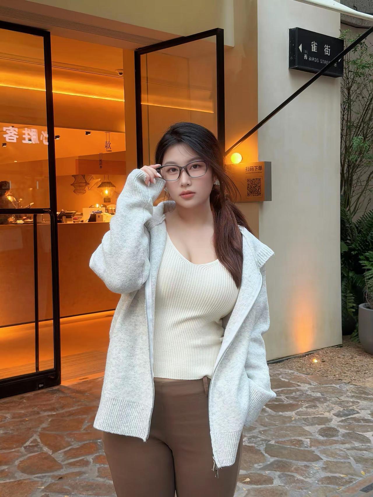 暖黄灯光裹着的小店门口，浅调穿搭刚好踩中今日的松弛节奏～软乎乎的针织开衫搭喇叭裤